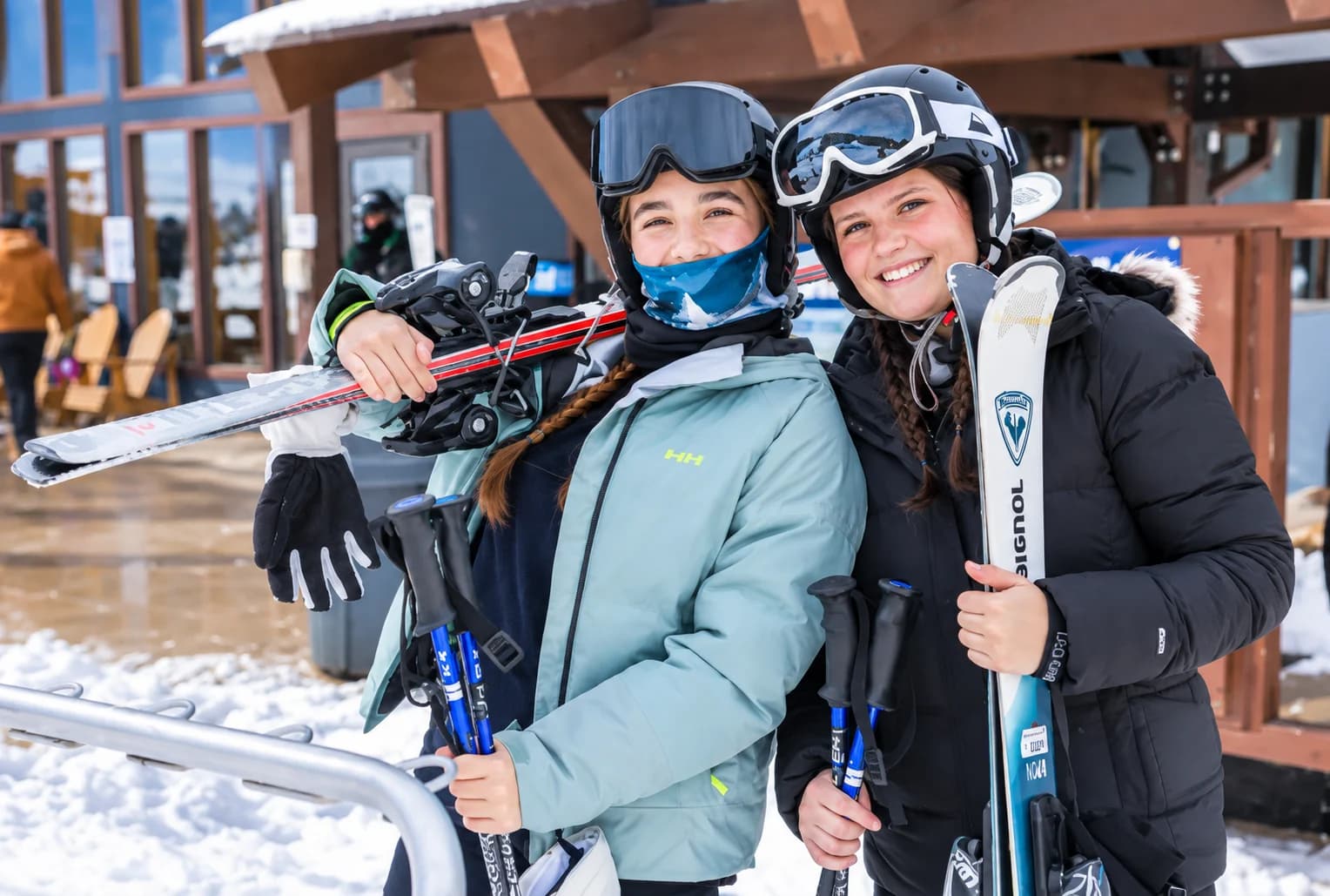 Two young people wearing helmets and goggles with their skis